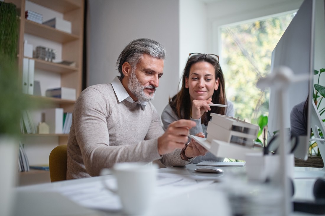 man and woman looking at architectural house model