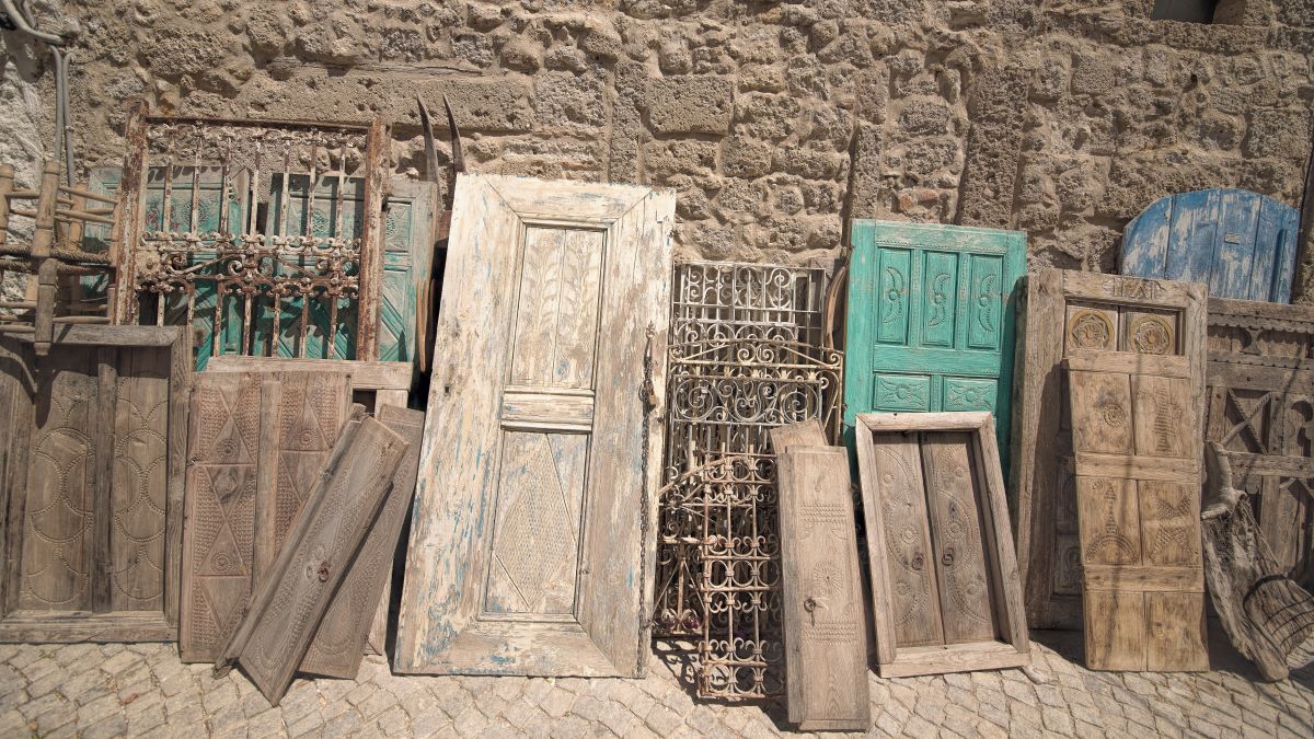 Old doors, gates, and shutters leaning against a wall